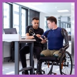 Two people sitting down looking at prosthetic device