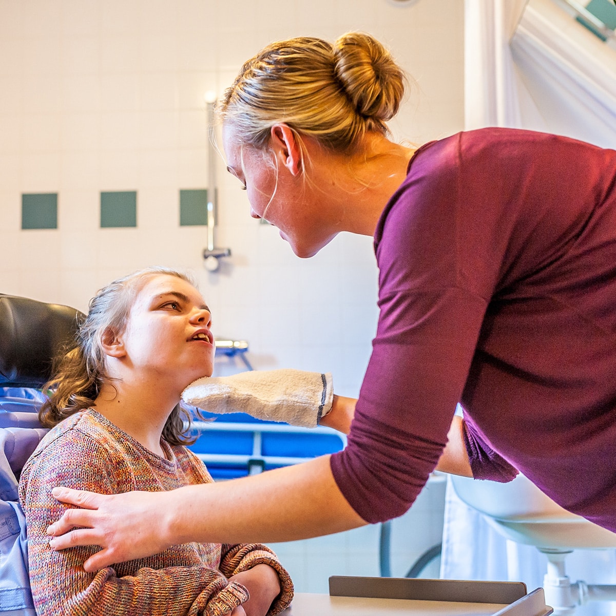 Disabled child in a wheelchair being cared for by a special needs care assistant